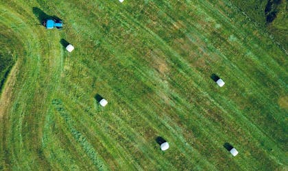 traktor torvastad grønn mark med høyballer