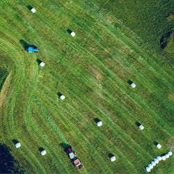 traktor torvastad grønn mark med høyballer