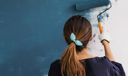kvinne som maler vegg blå