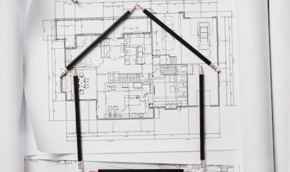 tegninger av hus på bord med nøkler, passer og målestokk som ligger rundt.