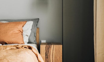 utsnitt av seng med nattbord og lampe