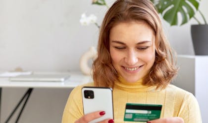 kvinne som holder bankkort og mobil