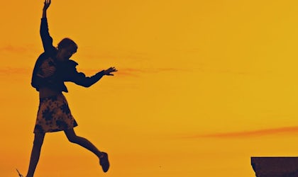 Kvinne som hopper langs strandkant i solnedgangen