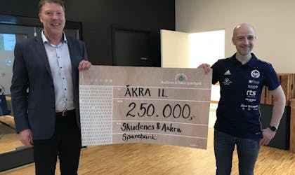 Banksjef og daglig leder Åkra Idrettslag holder sjekk på 250.000 kroner