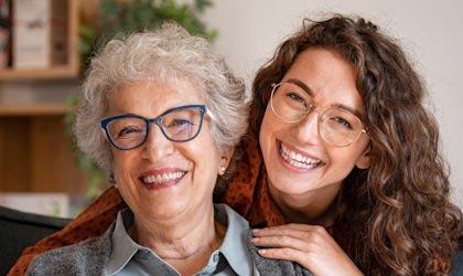 Ung kvinne som holder rundt eldre kvinne mens de smiler
