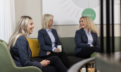 Tre ansatte i godt humør sitter i en sofa