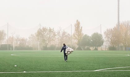 Person som bærer ballnett på en tom fotballbane