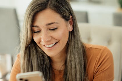 Smilende ung kvinne som ser på mobil