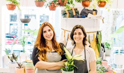 To ansatte i blomsterbutikk som holder blomster